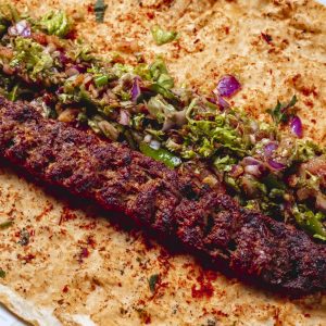 side view lulya kebab with red onion geens hot green pepper salt and pepper on pita
